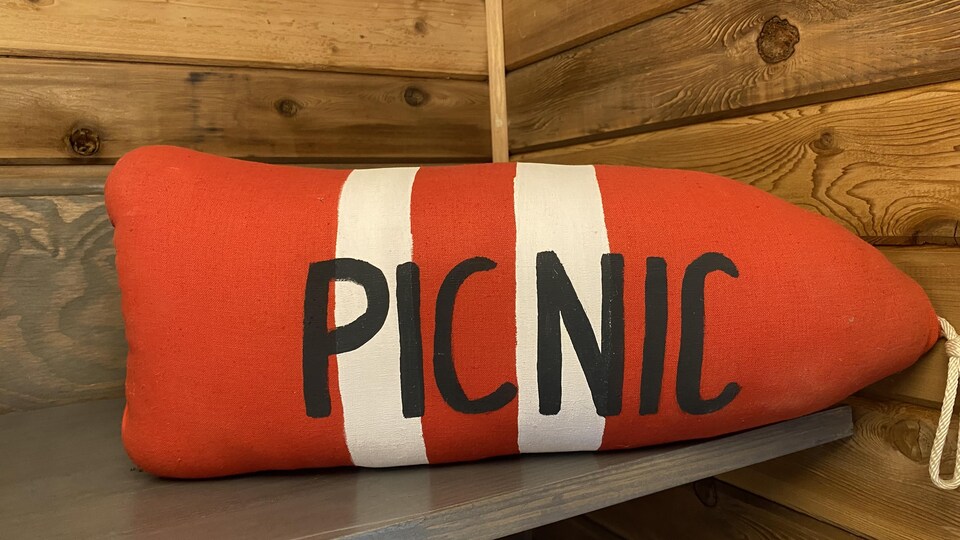Photographie d'une bouée de bateau orange et blanche sur laquelle est écrit le mot picnic.