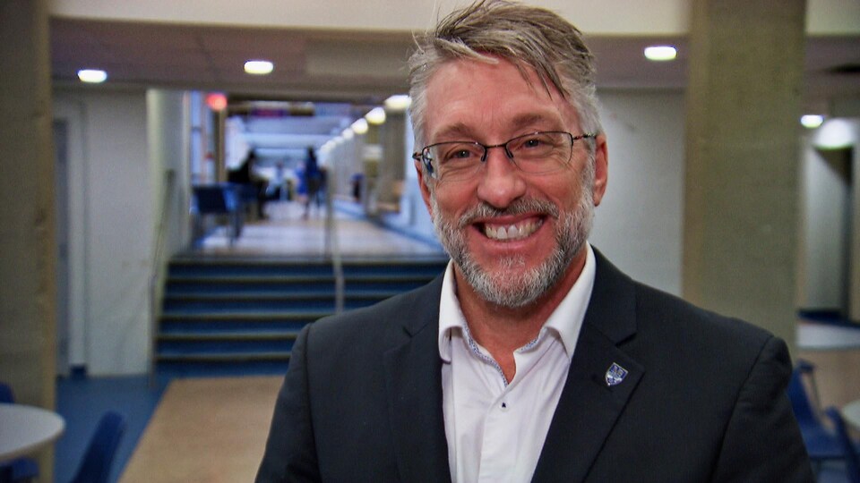 Un homme souriant dans un corridor d'école.