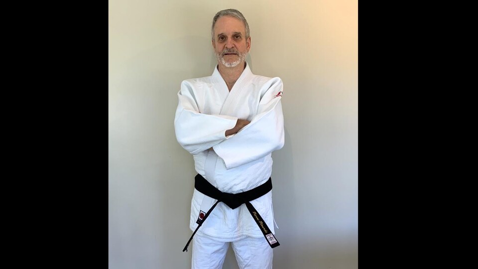 Le Dr Pierre Plourde est vêtu de son uniforme blanc de judoka. Il porte la ceinture noire.