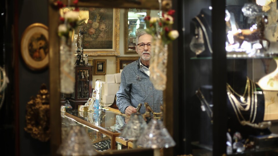 Pierre Saint-Denis, dans le reflet d'un miroir, au milieu d'objets.