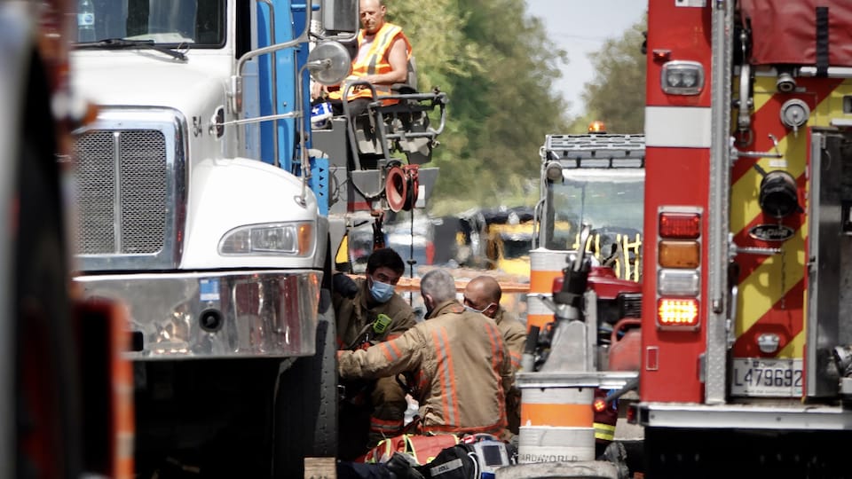 Des pompiers travaillent à dégager une personne sous un camion.