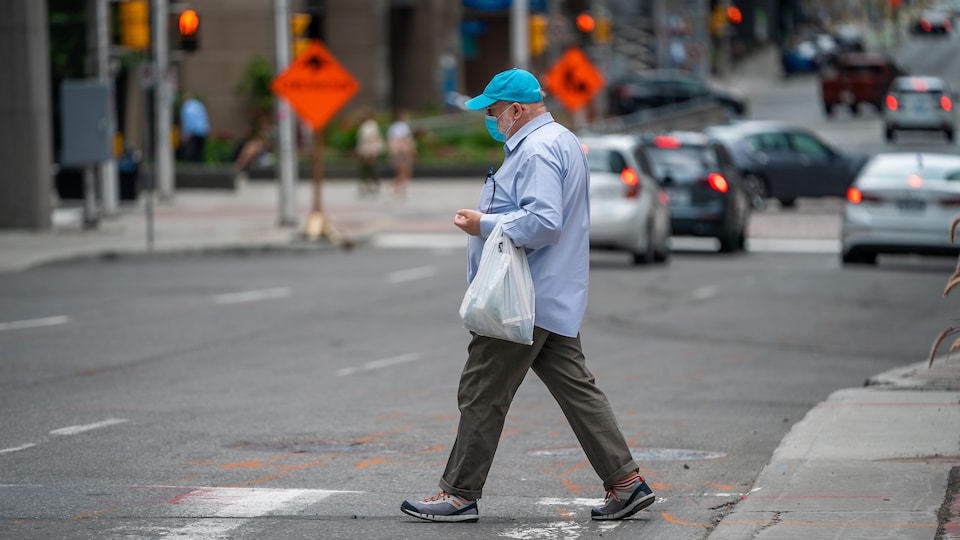 Un homme masqué traverse une rue d'Ottawa.