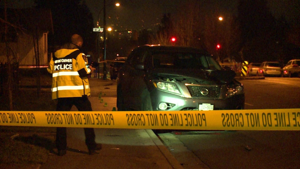 Un policier est debout devant le VUS Nissan qui a heurté un piéton samedi soir à Vancouver.
