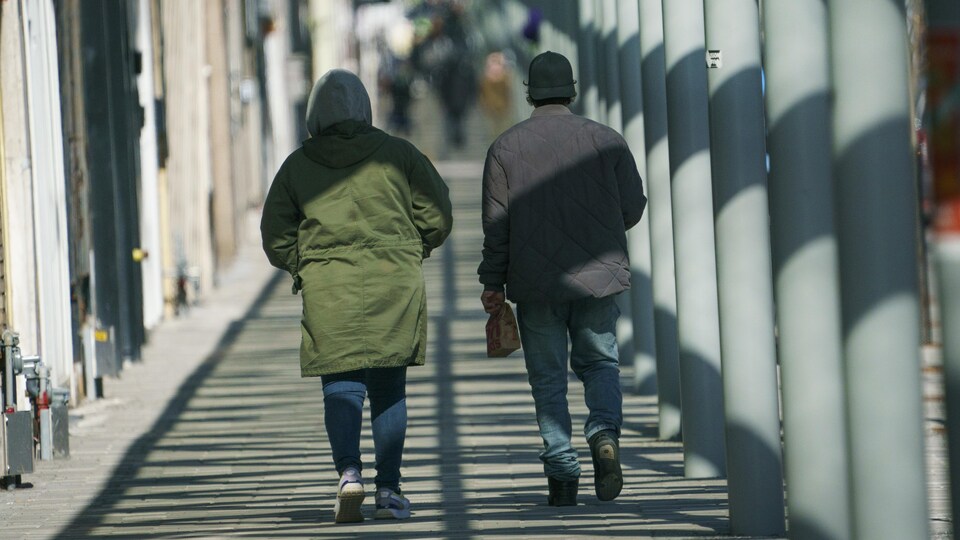 Deux personnes, de dos, marchent près de colonnes.