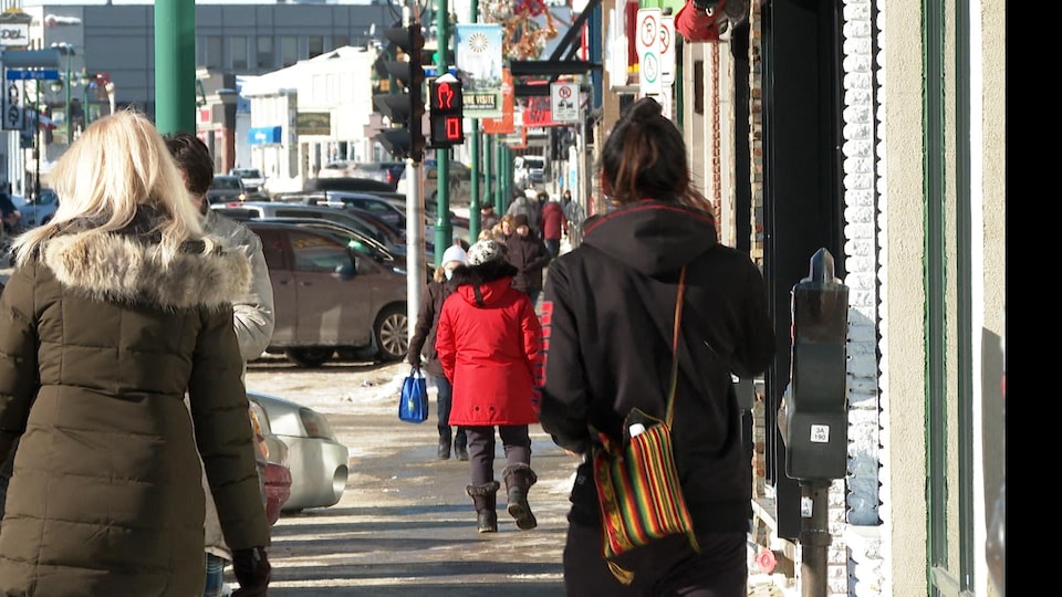 Des piétons circulent au centre-ville de Val-d'Or. Une personne porte un masque de procédure.