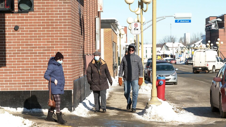 Des piétons circulent au centre-ville de Val-d'Or en hiver. Deux personnes portent un masque d'intervention.