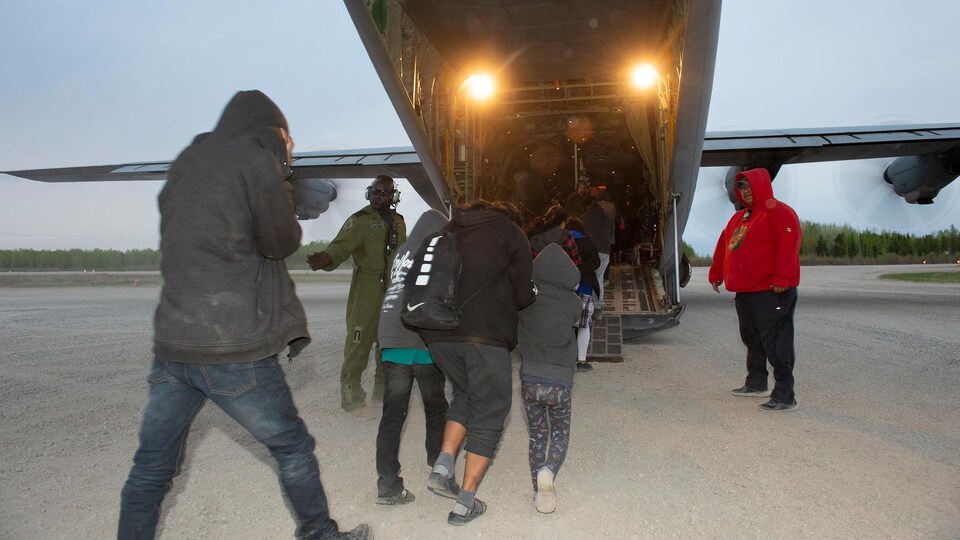 Des gens rentrent dans un avion Hercules.