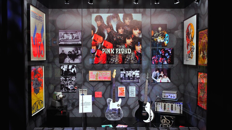 Des affiches du groupe Pink Floyd et des guitares dans un présentoir d'exposition. 