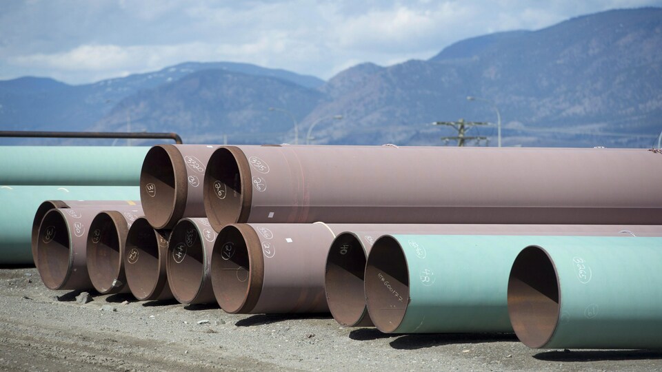 Des bouts de pipeline sur le sol devant les montagnes