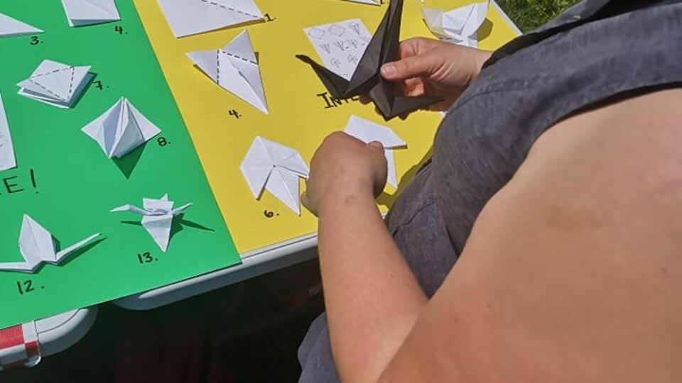 Une personne installe des morceaux de papier qui formeront l'origami sur des cartons de couleur.