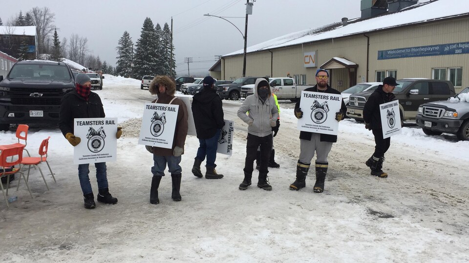 Des emplotés du CN tiennent des pancartes.