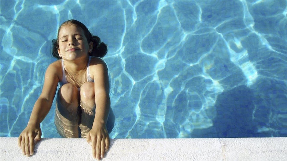 Une enfant se baigne dans une piscine.