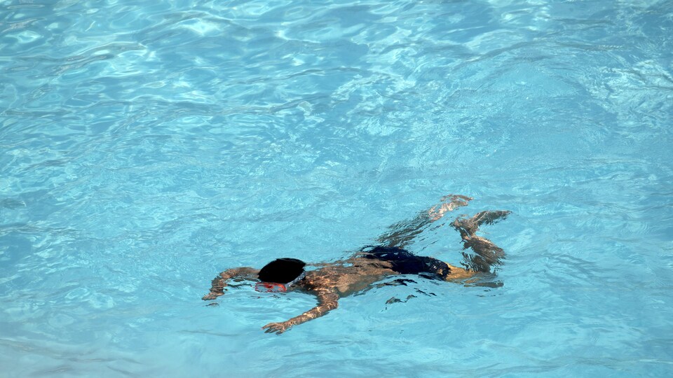 Un garçon nage dans une piscine.
