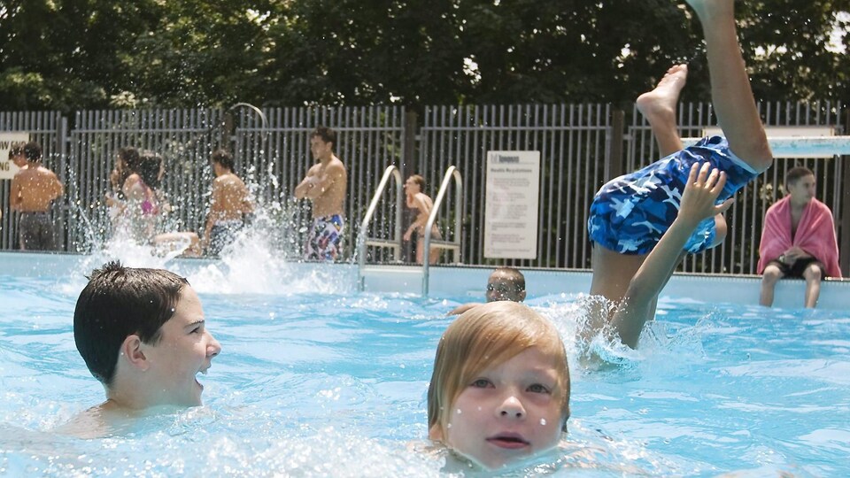 Des enfants se baignent dans une piscine extérieure.