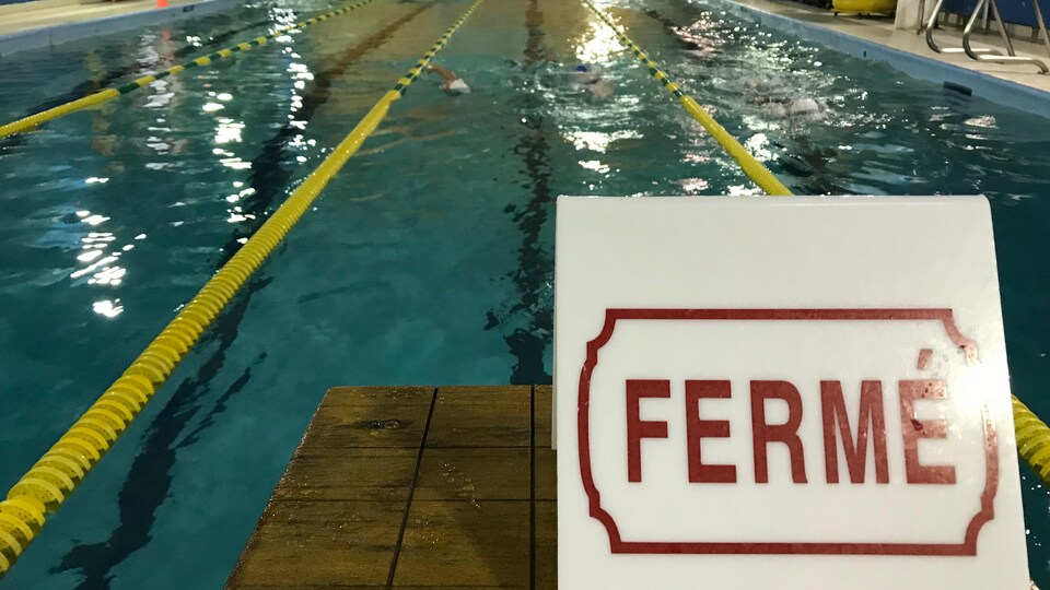 Une affiche indique fermé au bout d'un corridor de piscine sportive.