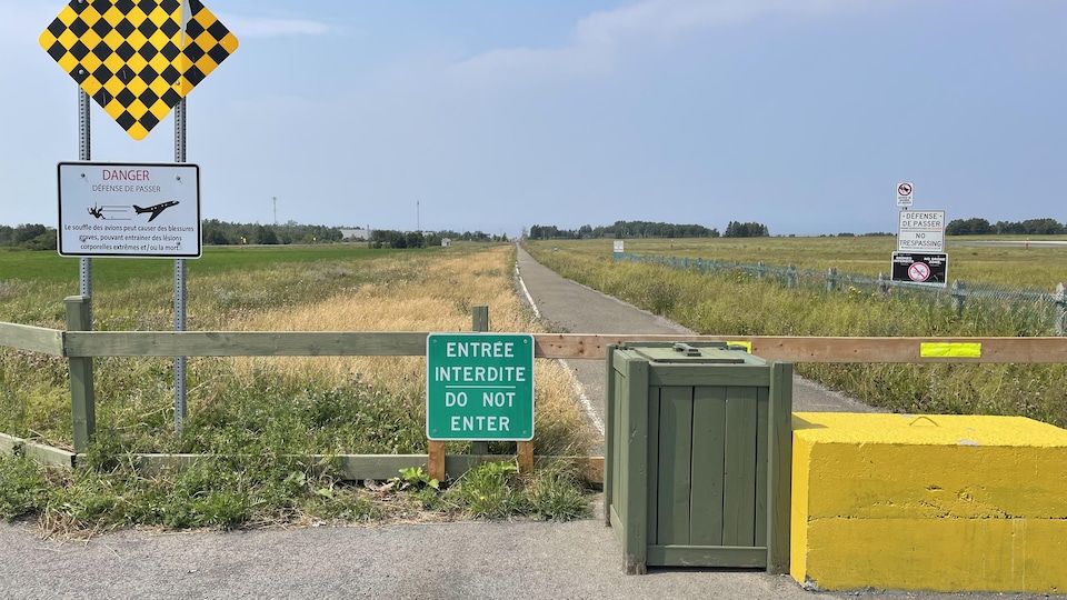 L'entrée de la piste cyclable est bloquée par un bloc de béton et une affiche indique l'interdiction d'accès.
