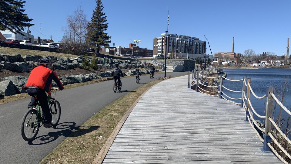 Des cyclistes roulent sur une piste cyclable longeant le lac Osisko.
