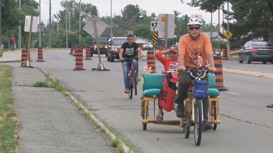 Des cyclistes utilisent une piste cyclable aménagée sur une voie de circulation normalement réservée aux voitures.
