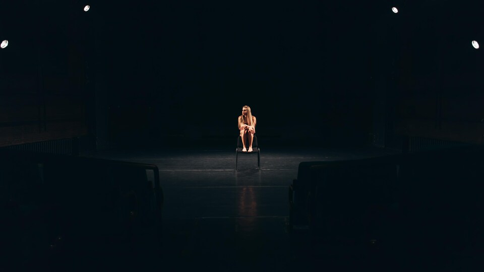 Une femme est assise au milieu d'une scène.