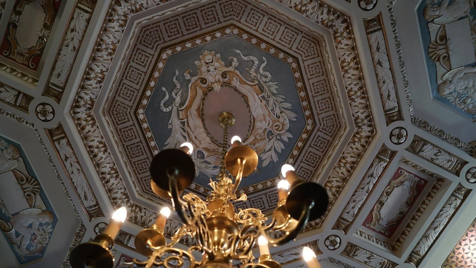 Un plafond richement décoré avec un chandelier.