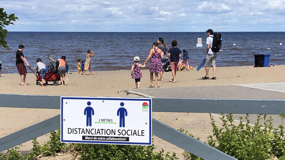 Des baigneurs se trouvent sur une plage bordant le lac Saint-Jean.
