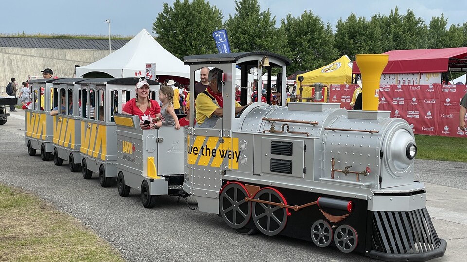 Des familles ont pris place dans les wagons tirés par une locomotive, aux couleurs de Via Rail.