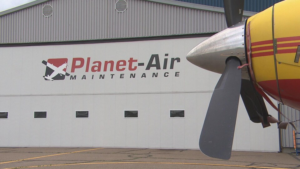 Une hélice d'avion devant un garage de Planet-Air Maintenance