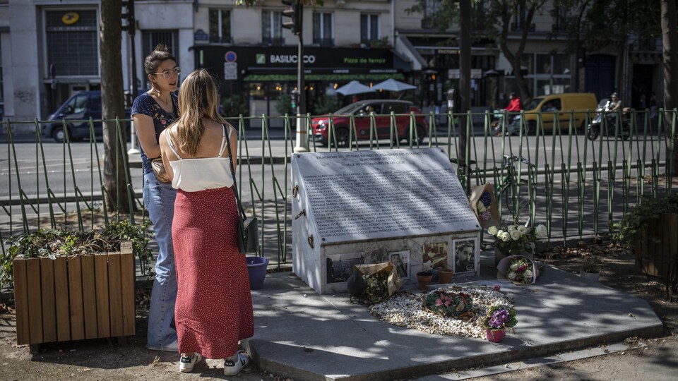 Deux femmes, près d'une plaque commémorative.