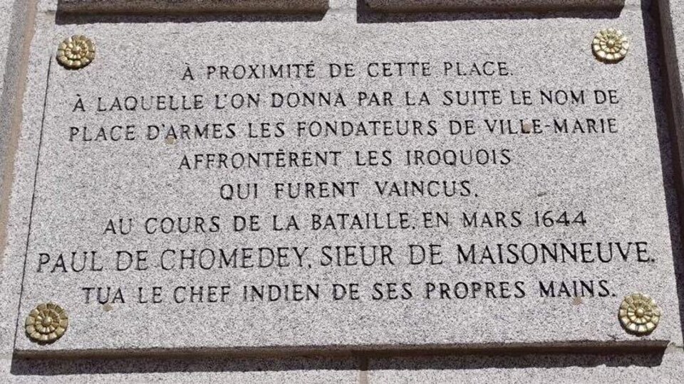 On peut lire : « À proximité de cette place à laquelle l’on donna par la suite le nom de place d’Armes, les fondateurs de Ville-Marie affrontèrent les Iroquois qui furent vaincus. Au cours de la bataille en 1644, Paul de Chomedey, sieur de Maisonneuve tua le chef indien de ses propres mains. »