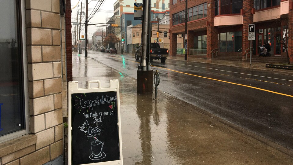 L'enseigne d'un café sur le trottoir sous une forte pluie.