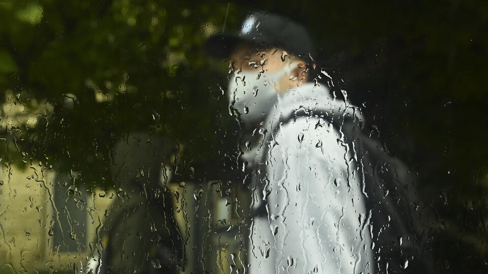 Un homme marche sous la pluie à Toronto.