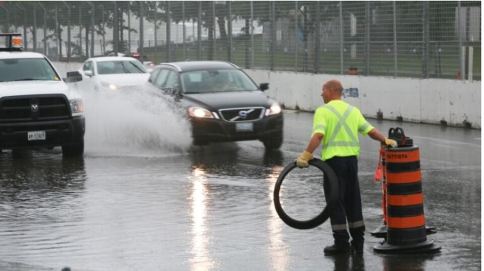 Un employé municipal barre la route sur le boulevard Lakeshore Ouest inondé.