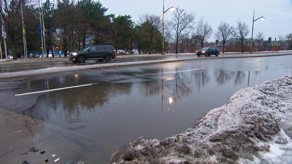 Une flaque d'eau occupe toute une voie d'une rue de Gatineau. Des voitures circulent dans les autres voies.