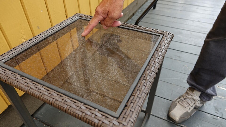 Un homme passe un doigt sur une table d'extérieur salie par une pluie toxique à Port-Daniel.