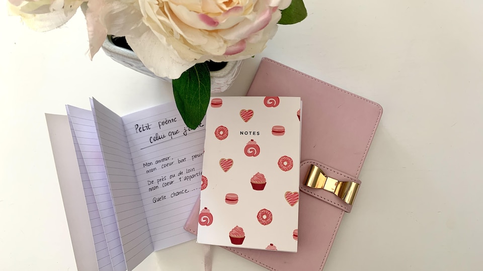 Des carnets de notes placés sur une table, près d'un bouquet de fleurs.