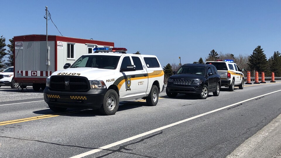 Des véhicules de police sont stationnés devant des cônes.