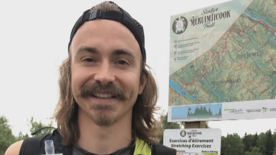 Rémi Poitras devant l'entrée d'un sentier pédestre.