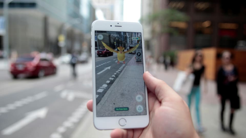 Un Pokémon Pidgey apparaît sur le téléphone d'un joueur de Pokémon Go dans une rue du centre-ville de Toronto.