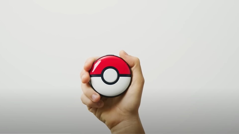 Une PokéBall dans la main d'une personne sur un fond blanc. 