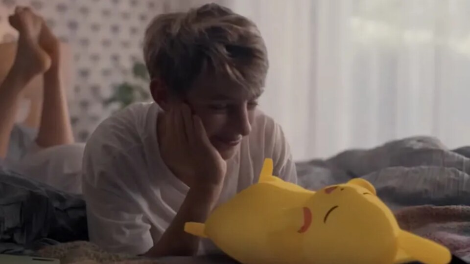 Un jeune homme regarde Pikachu dormir dans son lit. 
