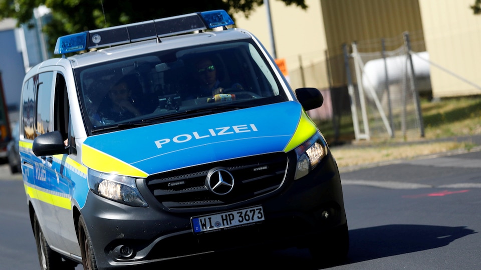 Une véhicule de police allemand roule sur une route.