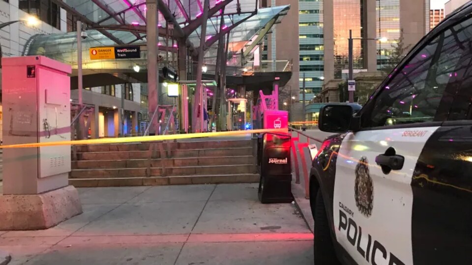 Une voiture de police devant une gare de train fermée.