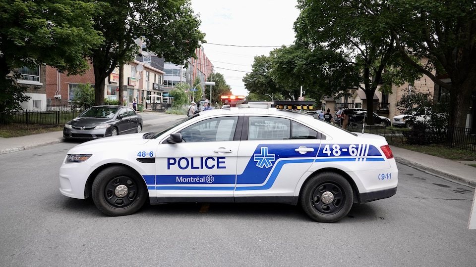 Une voiture de police stationnée en travers de la rue.