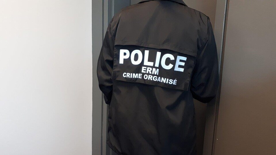 Un agent de l’Escouade régionale mixte en uniforme, de dos.