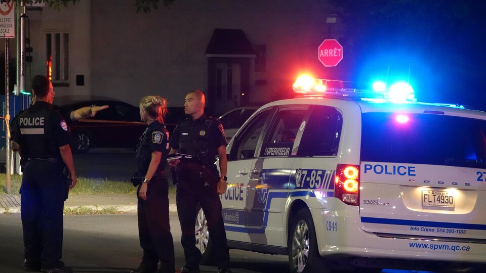 Des policiers se trouvent sur les lieux de l'incident et discutent avec un passant.