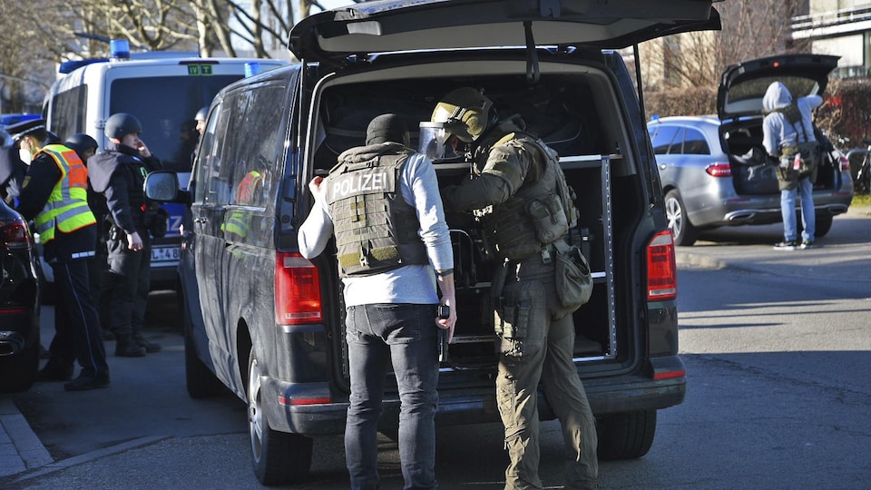 Des policiers près de camionnettes se préparent à intervenir.