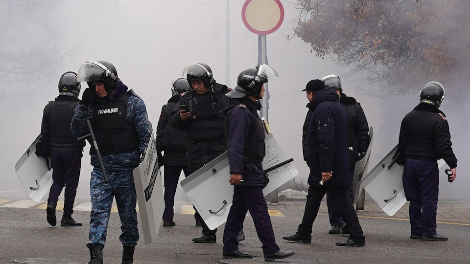 Des policiers munis de boucliers se tiennent dans une rue. 
