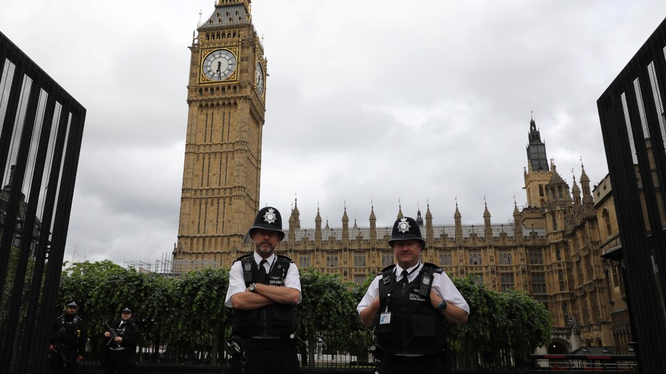Des policiers en uniforme gardent un portail menant vers le palais de Westminster à Londres.