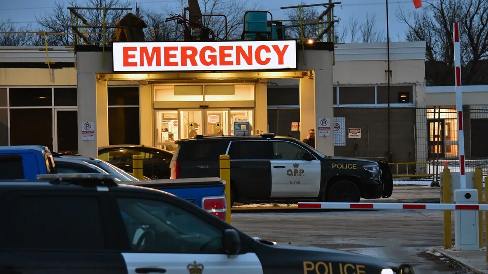 Deux autos de police sont stationnées devant un hôpital. 