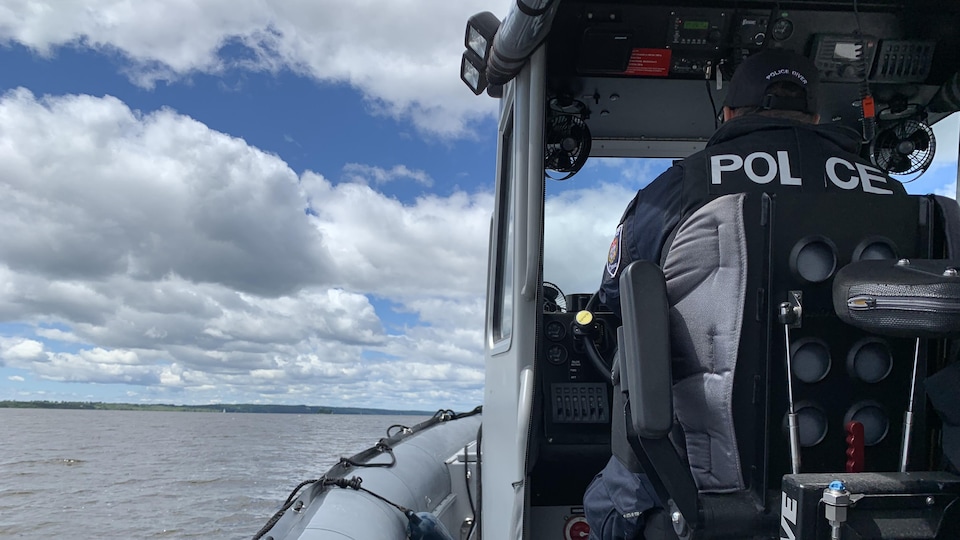 Un policier de dos qui pilote un bateau.